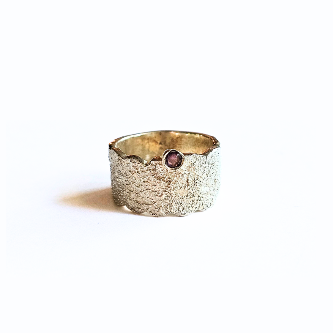 A textured silver ring with a faceted amethyst gemstone set in the center.