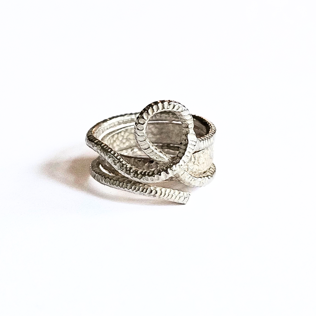 A silver woven knot ring with two interwoven hammered silver bands on a white background.