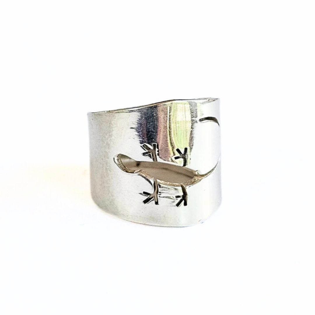 Sterling silver wide band ring with an open cut design resembling a gecko lizard positioned on a white background.