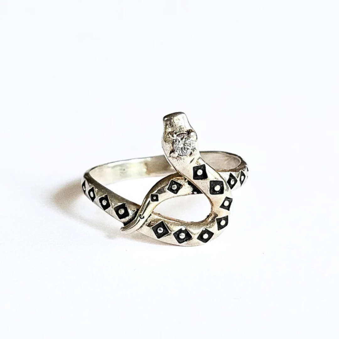 A sterling silver ring with a coiled snake design featuring a clear quartz gemstone set in the head of the snake.