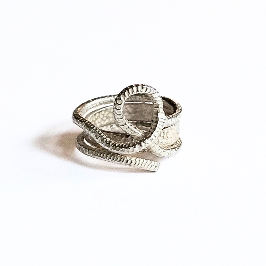 A silver woven knot ring with two interwoven hammered silver bands on a white background.