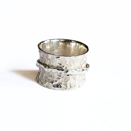 A sterling silver spinner ring with a textured surface and a rotating band, displayed against a white background.