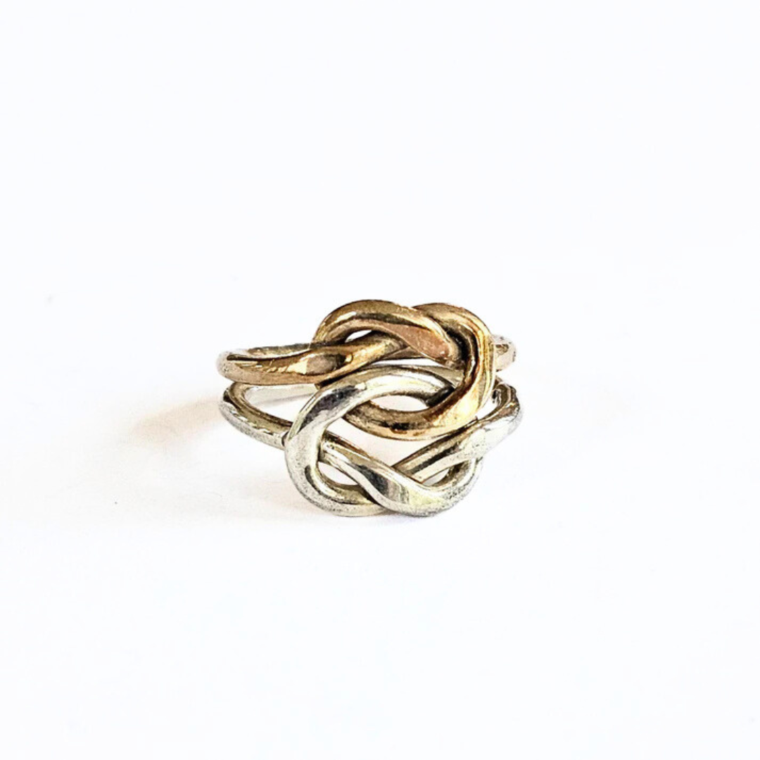 A sterling silver and brass knot ring on a white background.