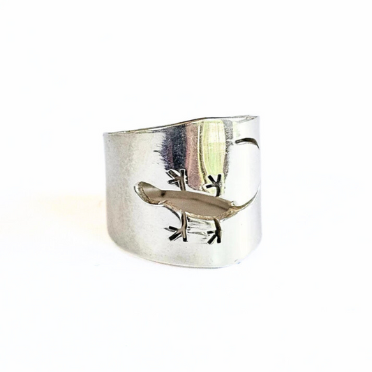 Sterling silver wide band ring with an open cut design resembling a gecko lizard positioned on a white background.