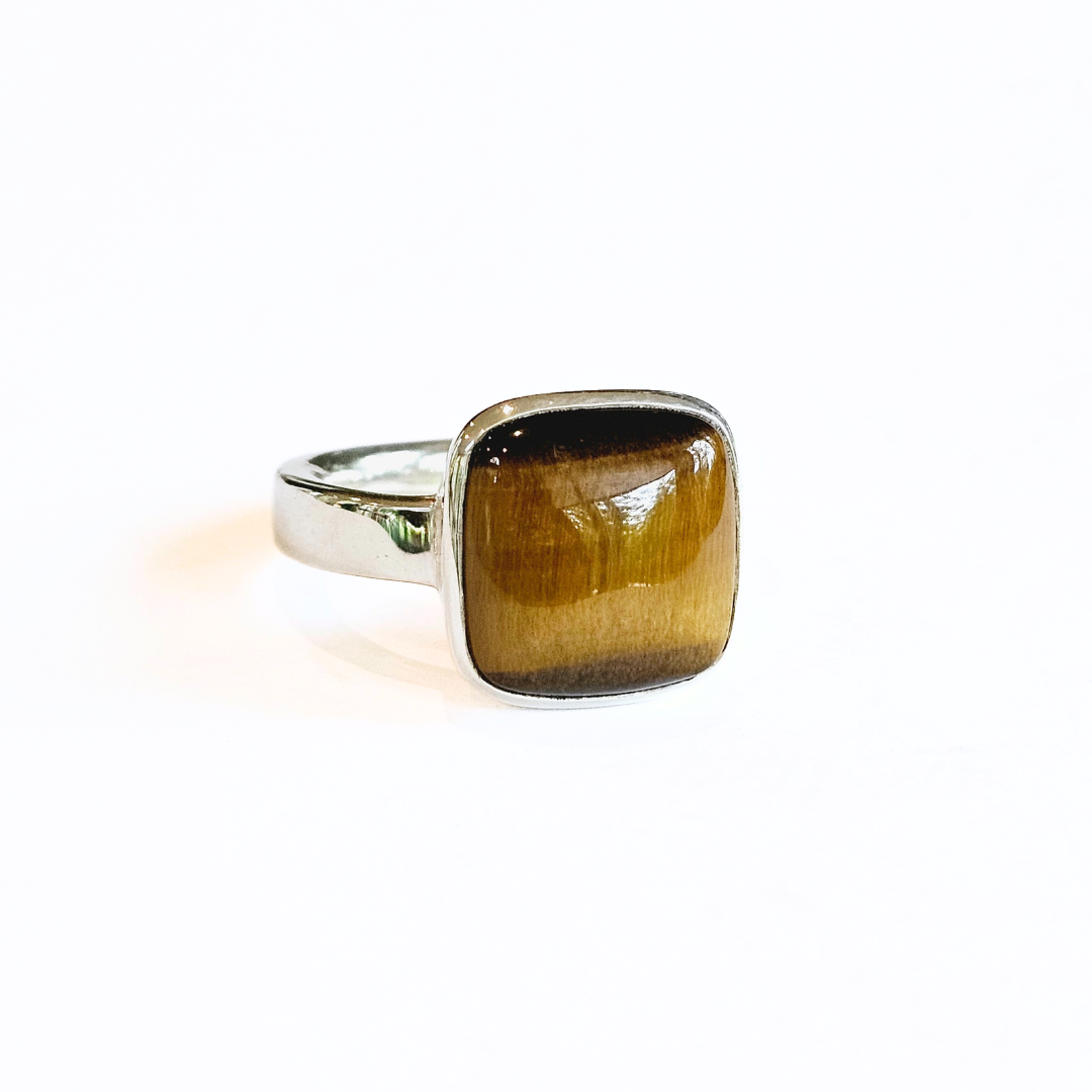 A sterling silver ring with a large Tiger Eye stone set in the center, on a white background.