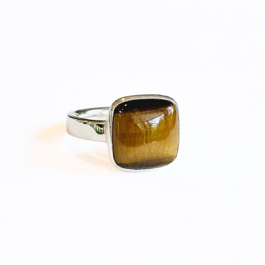 A sterling silver ring with a large Tiger Eye stone set in the center, on a white background.